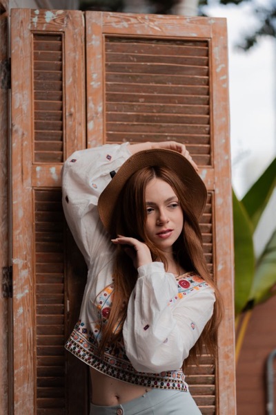 Woman in a hat and embroidered blouse by a wooden door