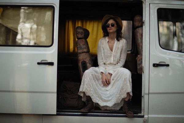 Woman in a white dress sitting in the doorway of a van